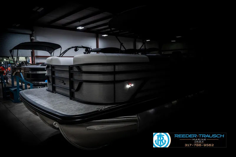 Slide: The Image of 2025 Bennington 22 SSB pontoon boat in a dimly lit showroom. - 4