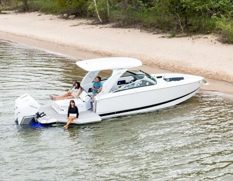 Slide: The Image of 2025 Four Winns H9C boat docked on a sandy beach with passengers relaxing. - 5