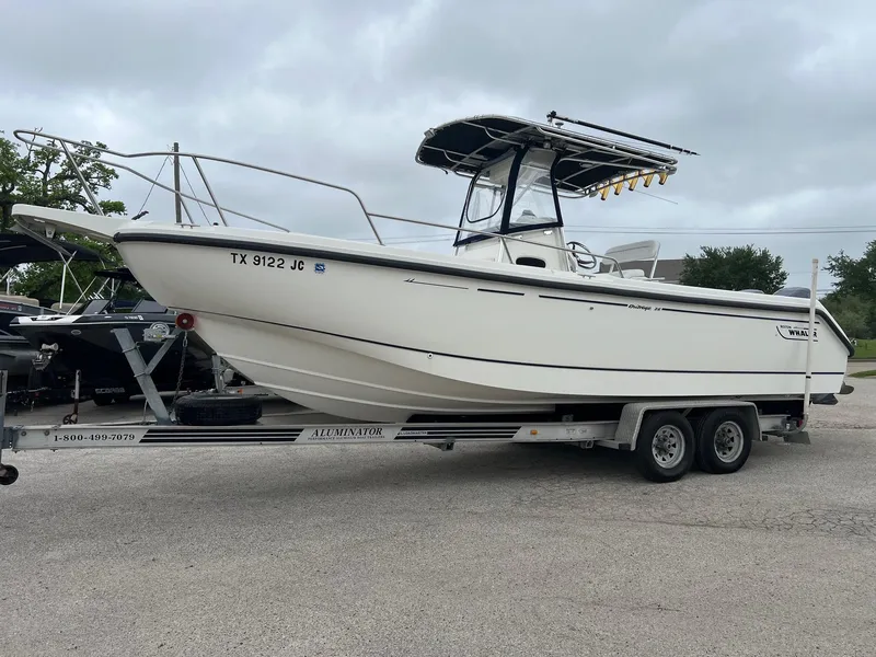 Slide: The Image of 1998 Boston Whaler 26 Outrage boat on trailer, parked outdoors under cloudy sky. - 0