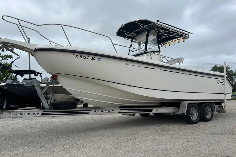 Slide: The Image of 1998 Boston Whaler 26 Outrage boat on trailer, parked outdoors under cloudy sky. - 19
