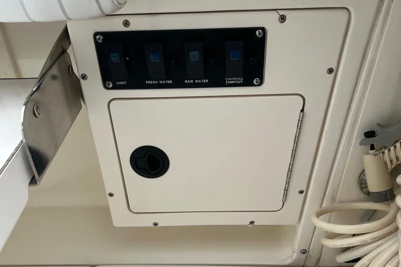 Slide: The Image of Control panel on a 1998 Boston Whaler 26 Outrage boat, featuring switches and storage compartment. - 21