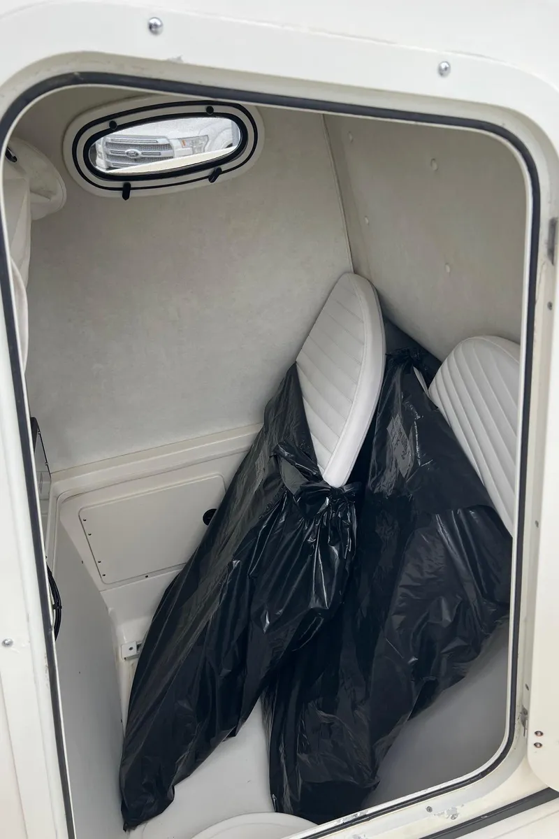 Slide: The Image of Storage compartment in a 1998 Boston Whaler 26 Outrage boat with cushions and a black cover. - 27