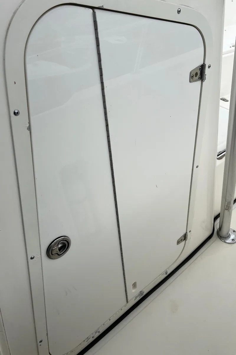Slide: The Image of 1998 Boston Whaler 26 Outrage boat compartment door, white with metal latch. - 29