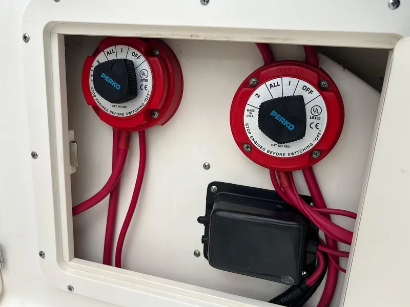 Slide: The Image of Battery switches on a 1998 Boston Whaler 26 Outrage boat, featuring red cables and Perko dials. - 6