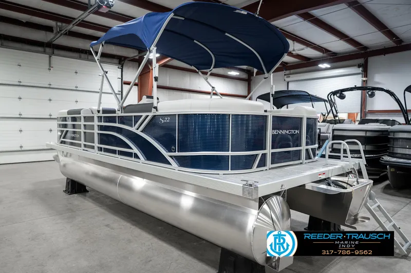 Slide: The Image of 2025 Bennington 22 SSR pontoon boat with blue canopy in a showroom. - 10