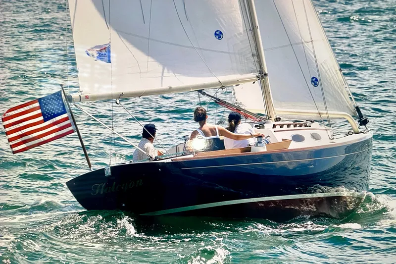Slide: The Image of Alerion Express 28 sailboat from 2002 sailing with American flag on open water. - 1
