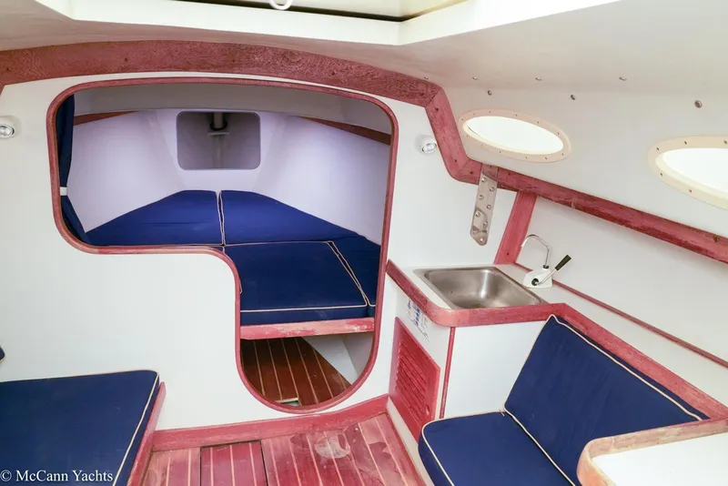 Slide: The Image of Interior of 2002 Alerion Express 28 sailboat with blue seating and compact kitchenette. - 11