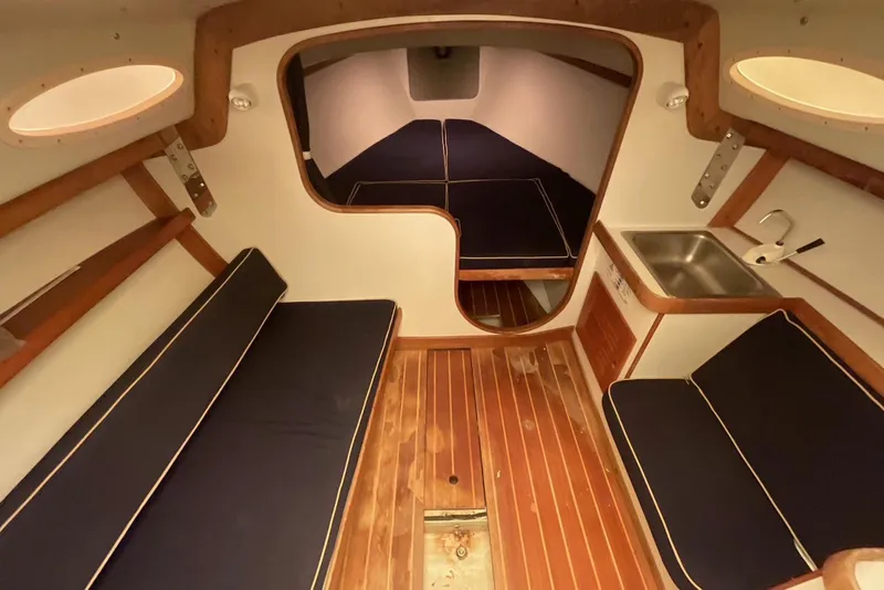Slide: The Image of Interior of a 2002 Alerion Express 28 sailboat with wooden flooring and navy seating. - 27