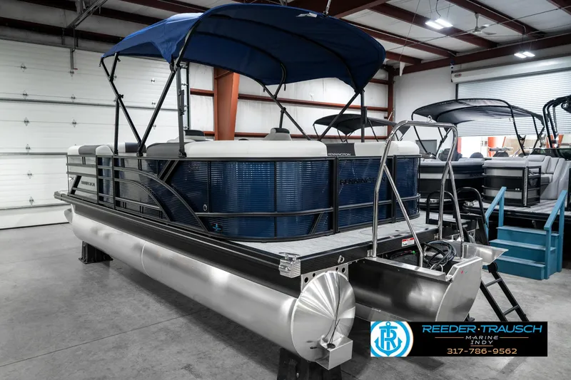 Slide: The Image of 2025 Bennington 22 SSR pontoon boat with blue canopy in showroom. - 10