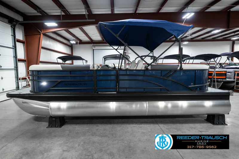Slide: The Image of 2025 Bennington 22 SSR pontoon boat with blue canopy in a showroom. - 11