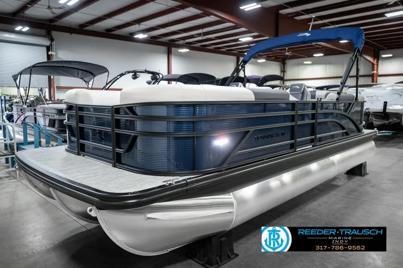 Slide: The Image of 2025 Bennington 22 SSR pontoon boat in showroom, featuring sleek design and blue accents. - 2