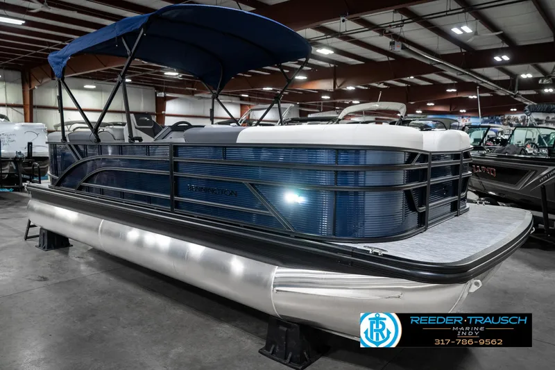 Slide: The Image of 2025 Bennington 22 SSR pontoon boat with blue canopy in showroom. - 6