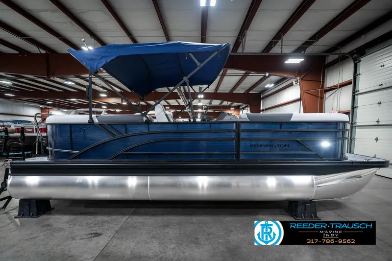 Slide: The Image of 2025 Bennington 22 SSR pontoon boat with blue canopy in a showroom. - 7