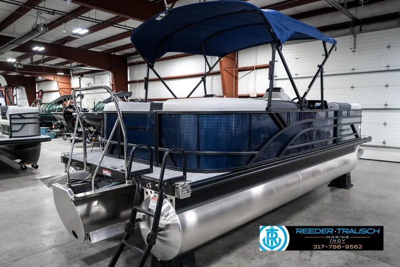 Slide: The Image of 2025 Bennington 22 SSR pontoon boat with blue canopy in a showroom. - 8