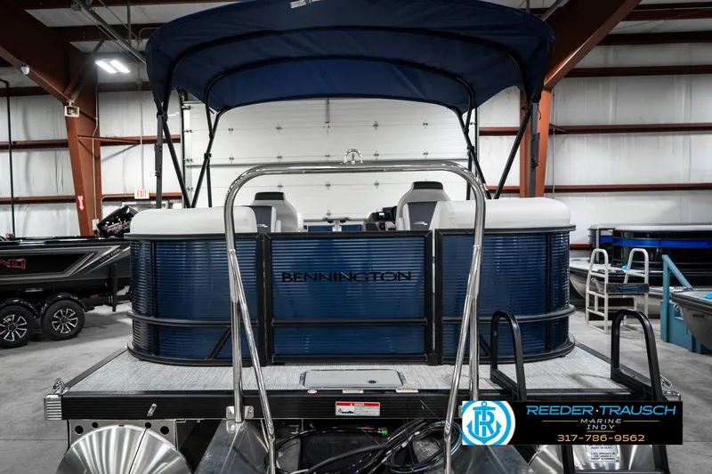 Slide: The Image of 2025 Bennington 22 SSR pontoon boat in showroom with blue canopy and seating. - 9
