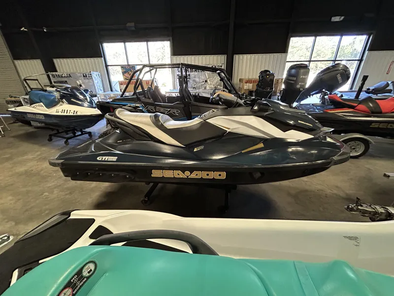 Slide: The Image of 2011 Sea-Doo GTI Limited 155 jet ski displayed indoors with other watercraft. - 3