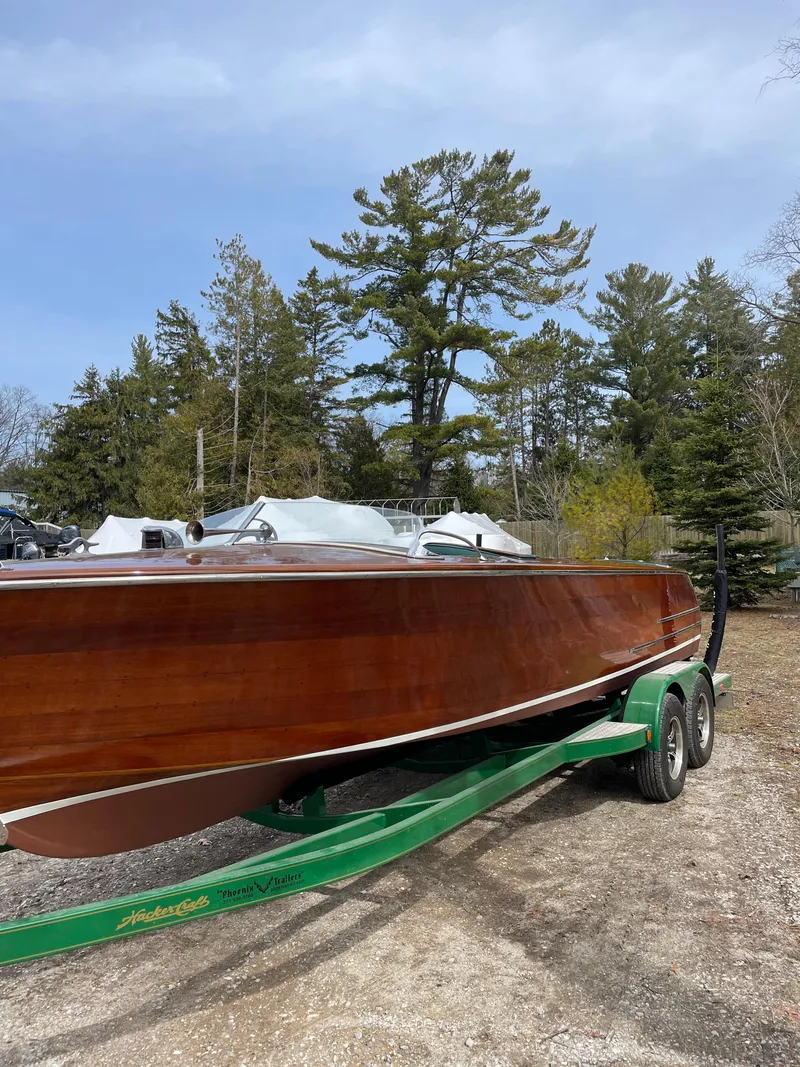 Slide: The Image of 1951 Hacker-Craft 22 Utility boat on a green trailer, surrounded by trees. - 10