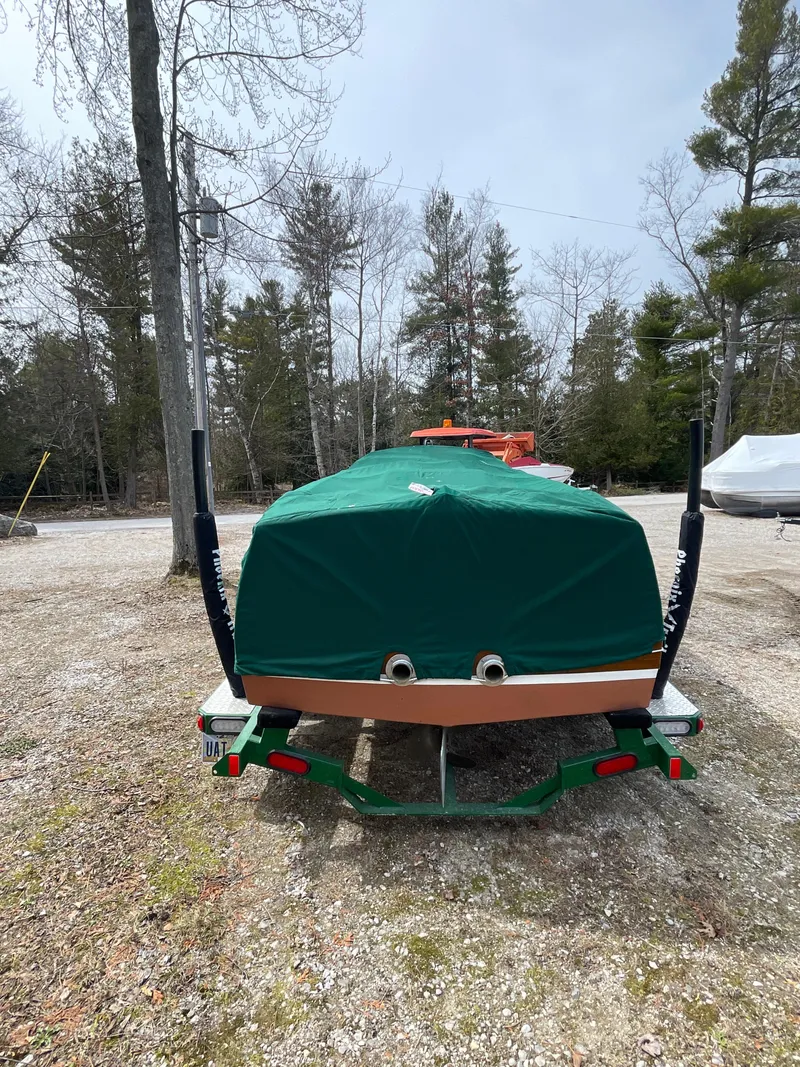Slide: The Image of 1951 Hacker-Craft 22 Utility boat covered, parked on a trailer in a wooded area. - 13