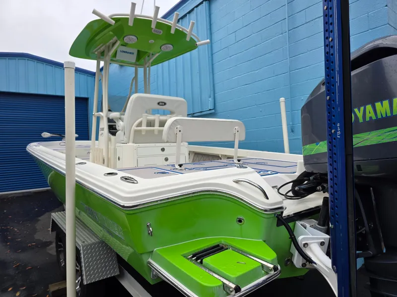 Slide: The Image of 2015 Pathfinder 2600 HPS boat with green accents, docked near blue building. - 12