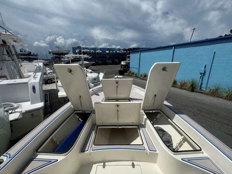 Slide: The Image of 2015 Pathfinder 2600 HPS boat with open storage compartments, docked under cloudy skies. - 22