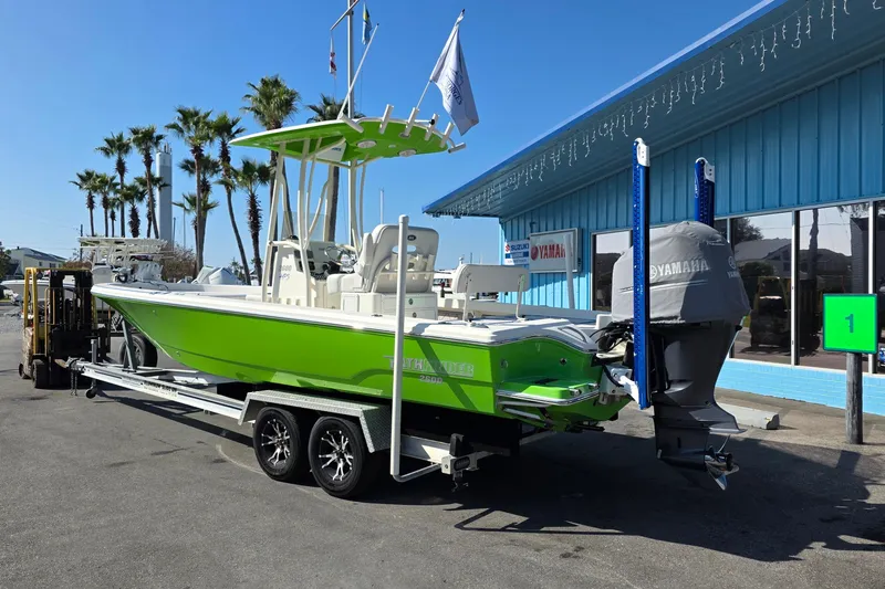 Slide: The Image of 2015 Pathfinder 2600 HPS boat in bright green on trailer, parked outside a blue building. - 3