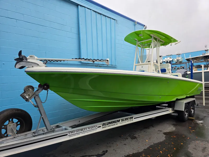 Slide: The Image of 2015 Pathfinder 2600 HPS boat in vibrant green on trailer, parked by blue building. - 4