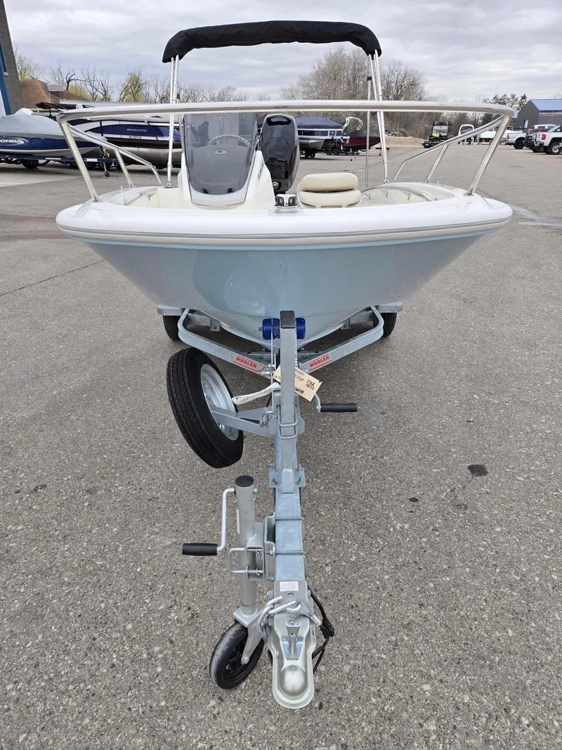 Slide: The Image of 2025 Boston Whaler 130 Super Sport boat on trailer, front view, parked outdoors. - 3
