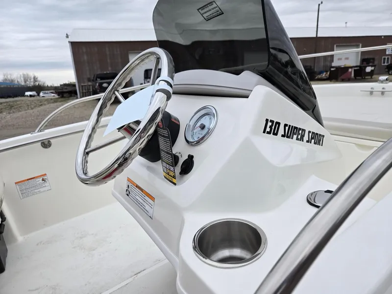 Slide: The Image of 2025 Boston Whaler 130 Super Sport boat dashboard with steering wheel and cup holder. - 6