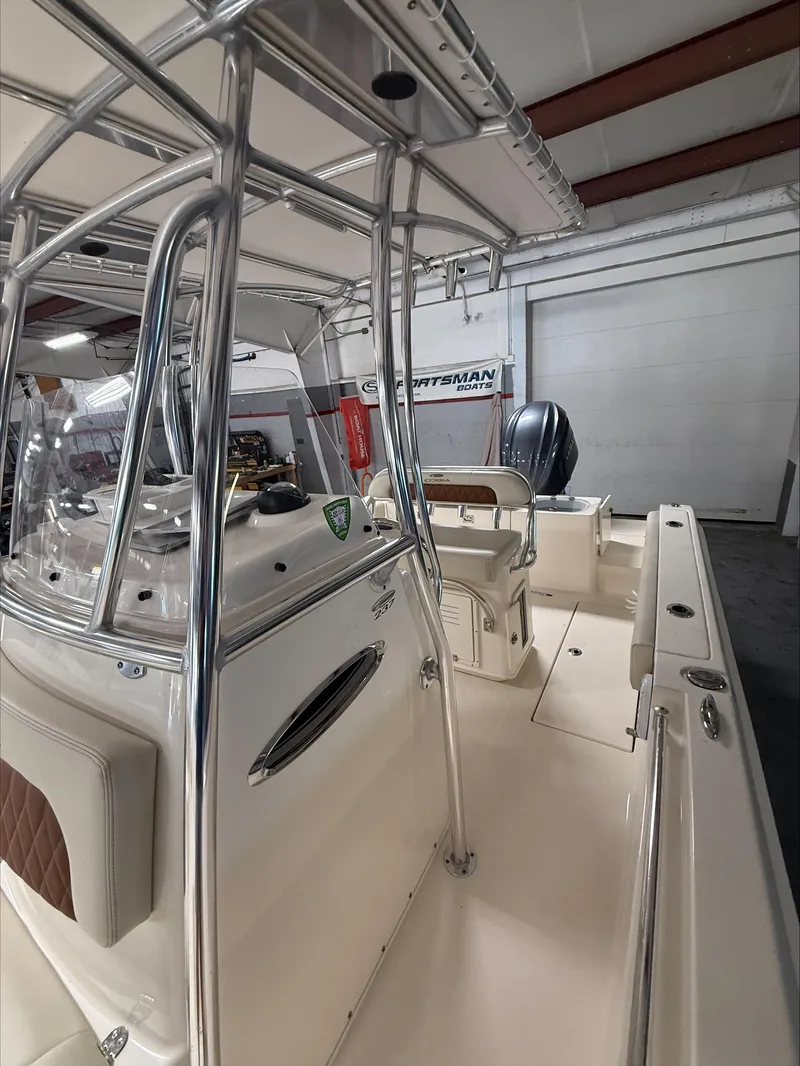 Slide: The Image of 2022 Cobia 237 CC boat interior with seating and console, in a showroom setting. - 15