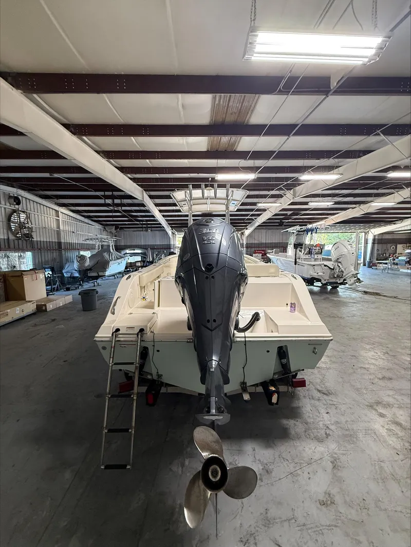 Slide: The Image of 2022 Cobia 237 CC boat in warehouse, rear view with outboard motor. - 5