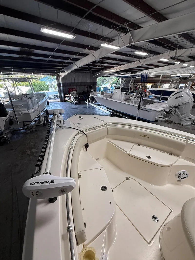 Slide: The Image of 2022 Cobia 237 CC boat in a showroom, featuring spacious deck and modern design. - 6