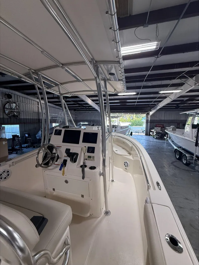 Slide: The Image of 2022 Cobia 237 CC boat interior in a showroom, featuring helm and seating area. - 8