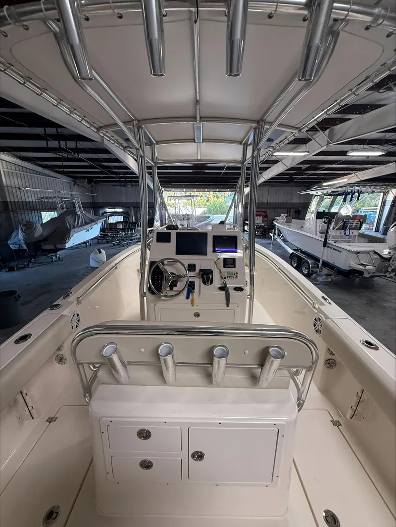 Slide: The Image of 2022 Cobia 237 CC boat interior with console and rod holders in a storage facility. - 9