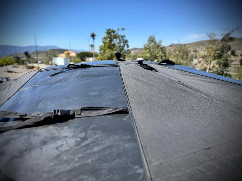 Slide: The Image of 2021 Malibu Wakesetter 25 LSV boat cover, secured with straps, outdoors on a sunny day. - 35