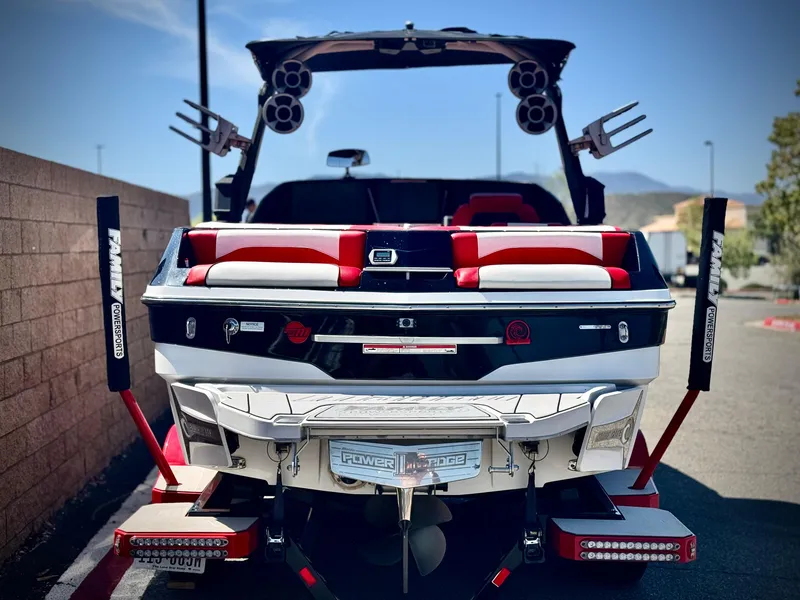Slide: The Image of 2021 Malibu Wakesetter 25 LSV boat, rear view, parked outdoors, featuring red and white seating. - 4