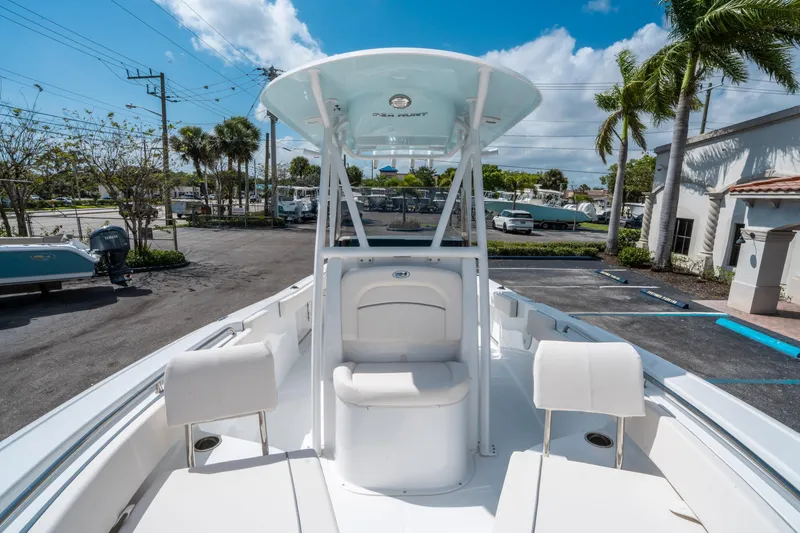 Slide: The Image of 2025 Sea Hunt Ultra 229 boat interior with seating, parked outdoors under a blue sky. - 24