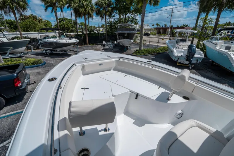 Slide: The Image of 2025 Sea Hunt Ultra 229 boat interior with seating, parked among other boats, surrounded by palm trees. - 25