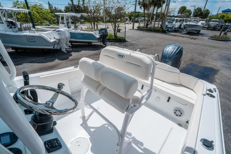Slide: The Image of 2025 Sea Hunt Ultra 229 boat interior with steering wheel and seating, parked outdoors. - 18