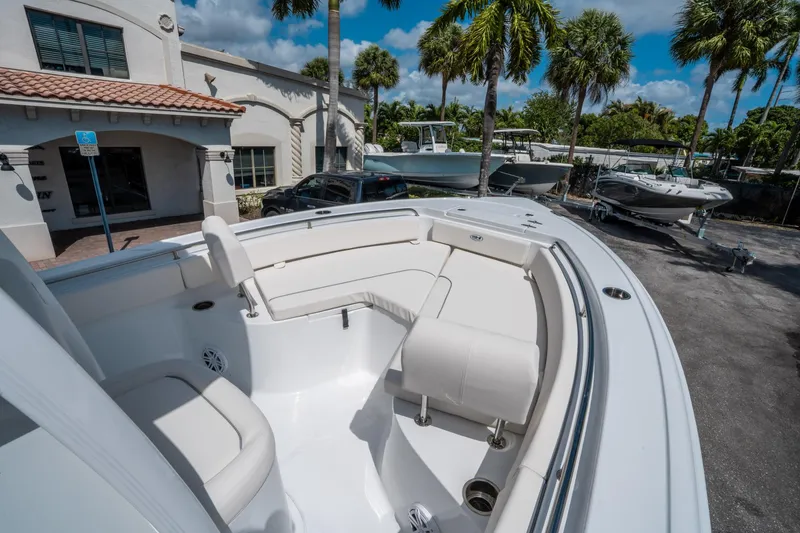 Slide: The Image of 2025 Sea Hunt Ultra 229 boat with spacious seating, parked outdoors under palm trees. - 23