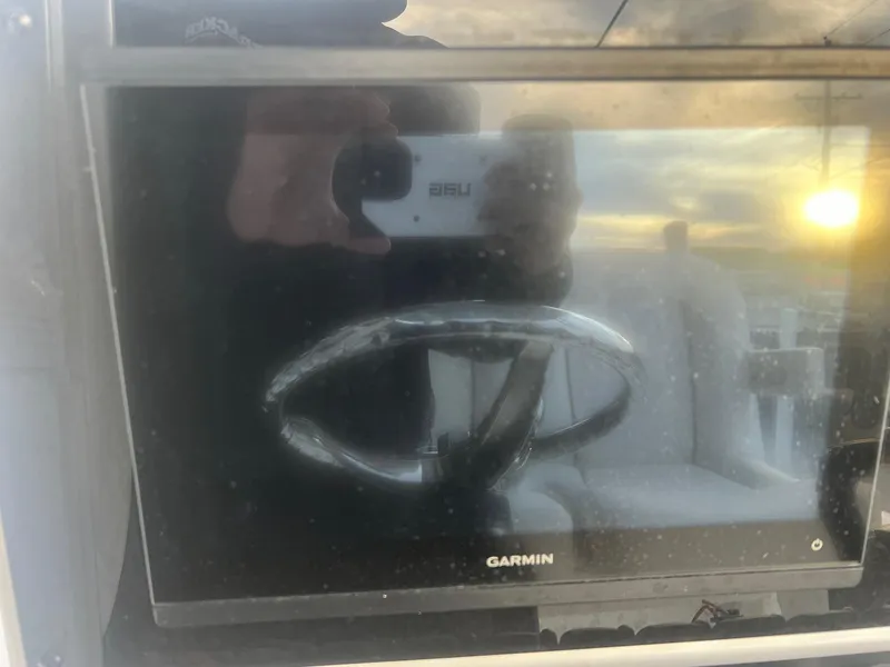 Slide: The Image of Garmin display on 2022 Sea Hunt BX 25 BR boat, reflecting steering wheel and sunset. - 13