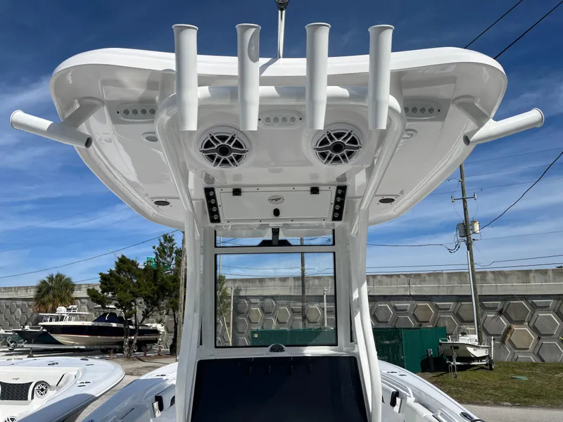 Slide: The Image of 2024 Tidewater 256 CC Adventure boat with T-top, rod holders, and speakers under a clear sky. - 6