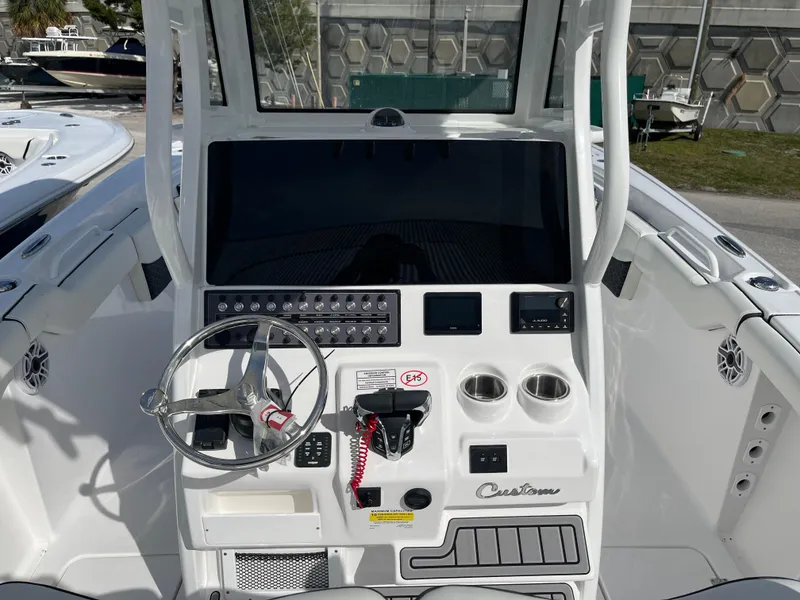 Slide: The Image of 2024 Tidewater 256 CC Adventure boat dashboard with steering wheel and control panel. - 7