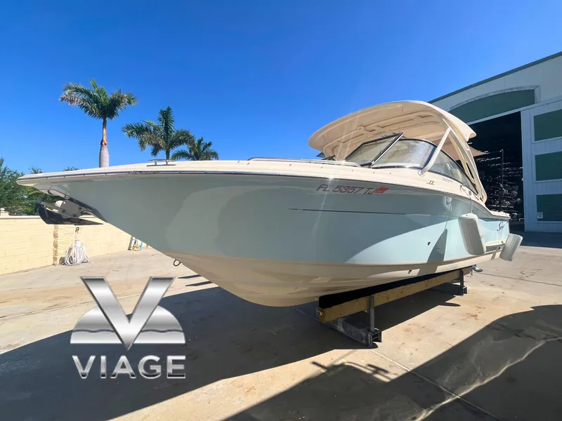 Slide: The Image of 2023 Scout 255 Dorado boat on display, sunny day, palm trees in background. - 0