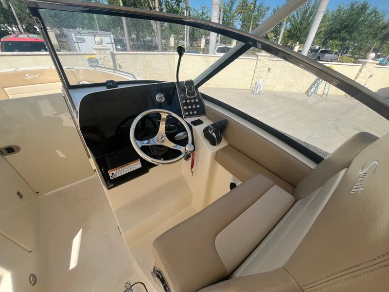 Slide: The Image of 2023 Scout 255 Dorado boat interior with steering wheel and beige seating. - 14