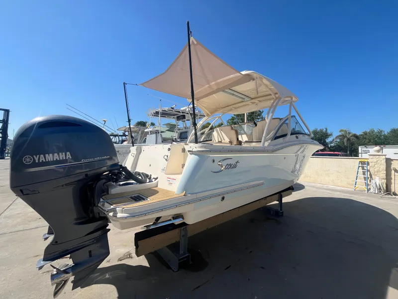 Slide: The Image of 2023 Scout 255 Dorado boat with Yamaha engine, docked under clear blue sky. - 2