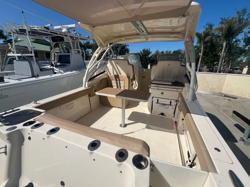 Slide: The Image of 2023 Scout 255 Dorado boat interior with seating and table, docked outdoors. - 6