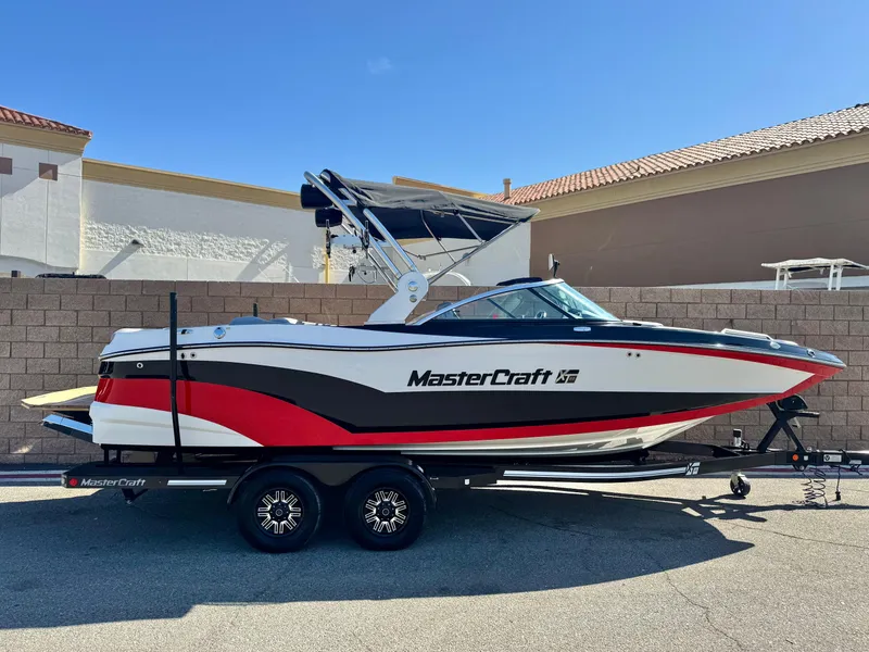 Slide: The Image of 2018 MasterCraft XT22 boat on trailer, red and white design, parked outdoors. - 0