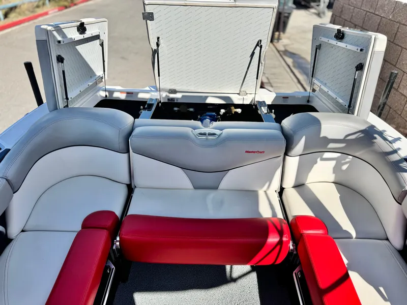 Slide: The Image of 2018 MasterCraft XT22 boat interior with red and white seating, open storage compartments. - 21