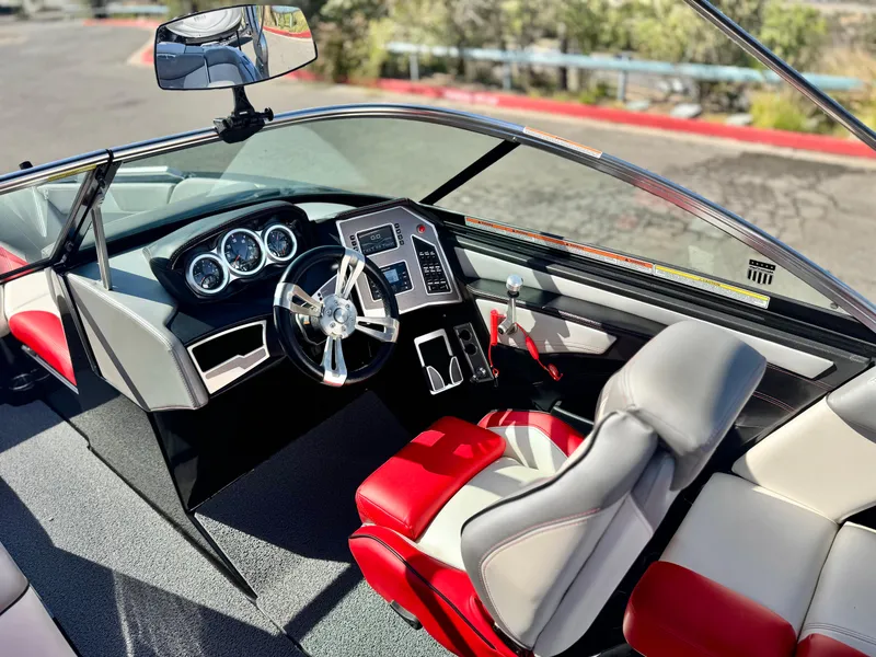 Slide: The Image of 2018 MasterCraft XT22 boat interior with red and gray seating, modern dashboard, and steering wheel. - 28