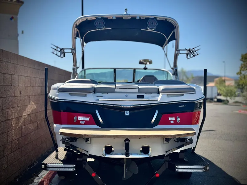 Slide: The Image of 2018 MasterCraft XT22 boat, rear view, parked outdoors on a sunny day. - 4